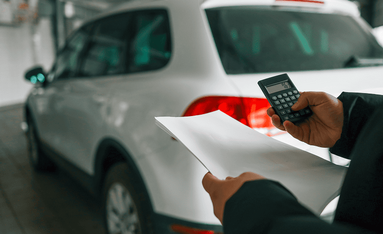 Man holding papers near parked vehicle
