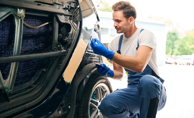 Mechanic repairing car body with tools